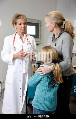 Une femme médecin parler à une mère et sa fille dans un bureau du médecin de l'hôpital Banque D'Images