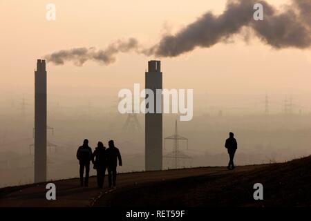 Personnes marchant sur Hoheward décharge publique, en face des cheminées de l'usine d'incinération d'AGR, Herten, Rhénanie du Nord-Westphalie Banque D'Images