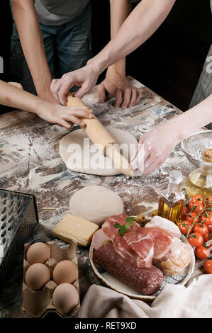 Femme avec enfant préparer la pâte à pizza maison. La tonalité de la lumière Banque D'Images