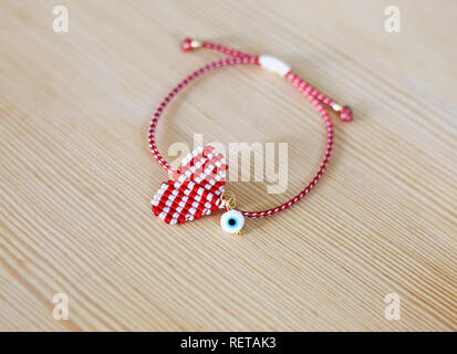 Le bracelet Mars traditionnel grec appelé Martaki en rouge et blanc - Macrame coeur forme avec petit oeil mauvais Banque D'Images