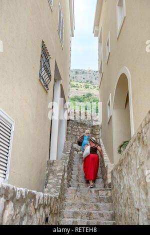 Les femmes sont deux étapes d'escalade en espace étroit entre le bâtiment à Sveti Stefan, le Monténégro. Banque D'Images