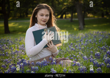 Girl Reading a book in fleurs bluebonnet Banque D'Images