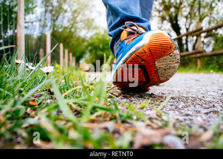 L'homme en jeans et chaussures de sport de marcher le long d'un chemin au printemps. L'accent sur la chaussure. Banque D'Images