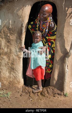 Les Masais mère et son enfant à l'entrée d'une cabane, Masai Mara, Kenya, Afrique de l'Est Banque D'Images