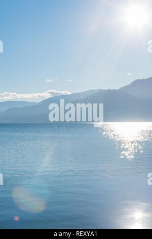 Ciel bleu et soleil sur lac et montagnes Banque D'Images