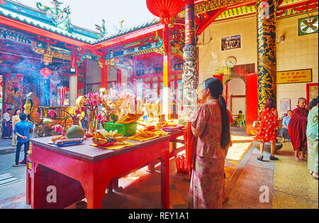 YANGON, MYANMAR - février 17, 2018 : La femme avec l'encens prie à l'autel avec des offrandes de fruits et de fleurs en Kheng Hock Keong Temple, sur F Banque D'Images