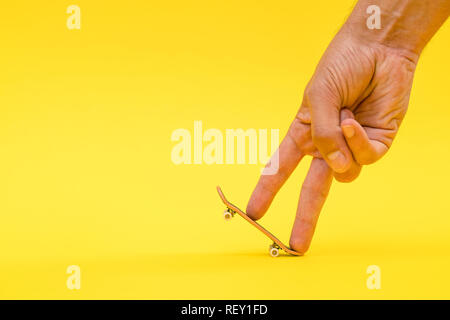 Touche. Une petite planche à roulettes pour les enfants et les adolescents à jouer avec les doigts de la main. Isolé sur fond jaune avec de l'espace pour le type Banque D'Images