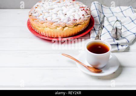 Délicieux petit cherry Pie saupoudrés de sucre glace sur la plaque whits tasse de thé sur la vieille table en bois blanc. Tarte aux cerises, série de décisions Banque D'Images