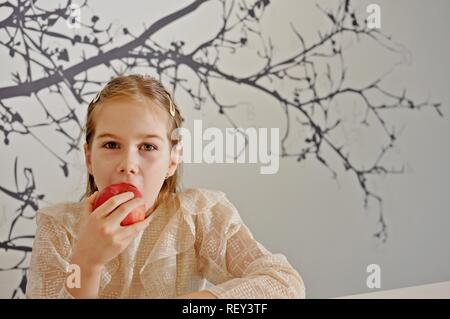 White Caucasian girl (enfant, kid) manger une pomme rouge. Copier du texte Banque D'Images