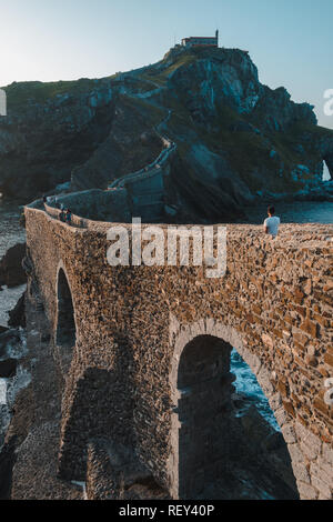 L'homme regardant San Juan de Gaztelugatxe's Chapel au coucher du soleil, Pays Basque Banque D'Images