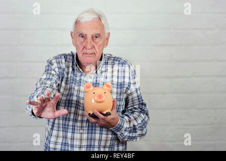 Man avec une tirelire sur fond brique Banque D'Images