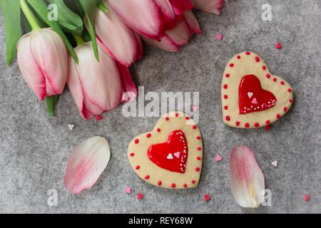 Valentines Day cookies coeur givré avec des tulipes roses fond, overhead view Banque D'Images