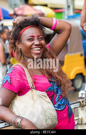 Nosy Be, Madagascar - Janvier 17th, 2019 : une femme malgache locale avec tenue colorée de rire, se penchant sur la rambarde au commer Banque D'Images