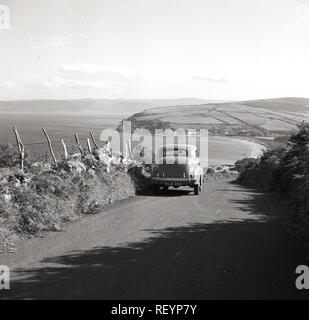 Années 1950, historiques, une voiture Austin de l'époque mis en garde sur la colline sur un chemin de campagne en Co. Antrim donnant sur l'océan Atlantique en Irlande du Nord. Antrim est célèbre pour son magnifique route côtière, la route côtière de la chaussée Banque D'Images