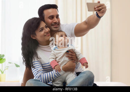 Jeune famille en tenant avec selfies Smart phone on bed Banque D'Images