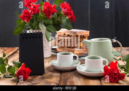 Gaufres Belges pour le petit-déjeuner pour deux. Des pâtisseries et un bouquet de roses rouges sur la table. Délicieux déjeuner romantique. Photo pour la Saint-Valentin Banque D'Images