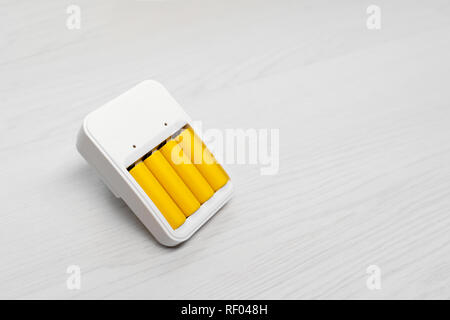 Photo de chargeur avec quatre piles jaune sur fond gris vide Banque D'Images
