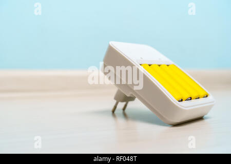 Photo de chargeur avec deux batteries jaune sur fond bleu vide Banque D'Images