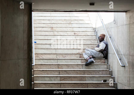 Lisbonne, Portugal, le 30 septembre, 2018 : Dirty personne sans-abri assis dans les escaliers et froid seul Banque D'Images