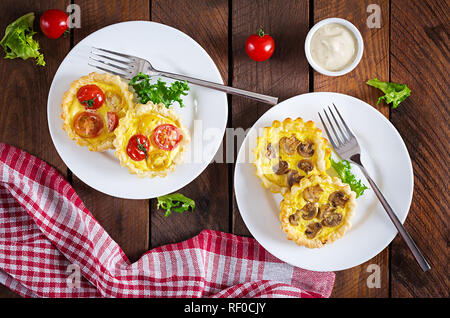 Les champignons, cheddar, tomates tartelettes sur fond de bois. Mini tartes. Délicieux apéritif, tapas, snack. Vue d'en haut. Mise à plat Banque D'Images