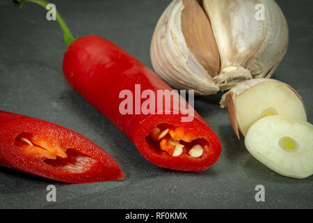 Près d'un piment rouge frais et l'ail coupé à tranches sur fond de plaque en ardoise noire, low angle view Banque D'Images