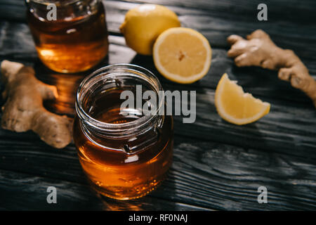 Focus sélectif de thé dans un bocal en verre sur la table en bois avec des racines de gingembre et citrons Banque D'Images