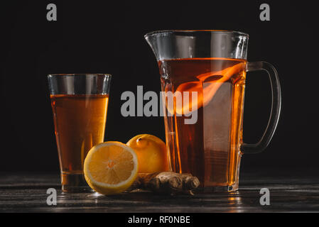 Plateau de citrons et le gingembre dans du verre et jar sur table en bois isolé sur black Banque D'Images
