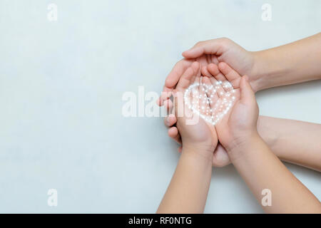 L'amour pur concept. Mains du bébé sont placées sur les mains de la mère. Il représente une protection et de soins. Le cœur a été créé par le programme. Banque D'Images