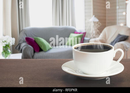 Tasse de café noir sur la table d'en salon moderne dans un style rustique avec chaise, divan mou. Banque D'Images
