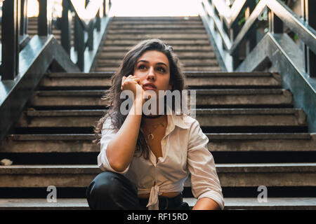 Portrait of young woman sitting on stairs Banque D'Images