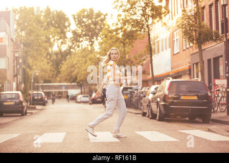 Young woman walking on zebra crossing