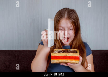 Petite fille aux bonbons dans fort surpris tenant une canne. Joyeux Noël et Nouvel An. Banque D'Images