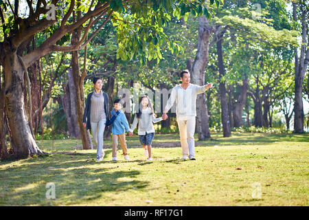 Famille avec deux enfants asiatiques marche main dans la main à l'extérieur dans le parc. Banque D'Images