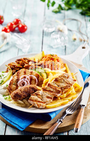 Plaque grill Grec traditionnel avec un assortiment de viandes grillées, de tomates épicées, riz croustilles de pommes de terre frites et des raita yaourt avec copie espace Banque D'Images