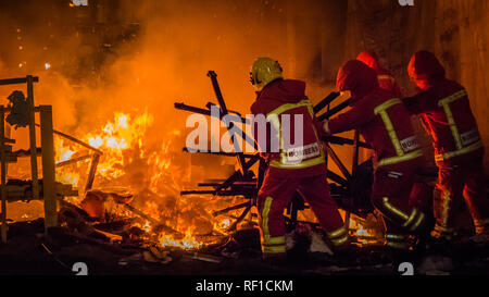 Les Pompiers au travail en uniforme en de de l'incendie en mettant les restes d'une falla sculpture en papier à Las Fallas festival à Cullera, Valenci Banque D'Images