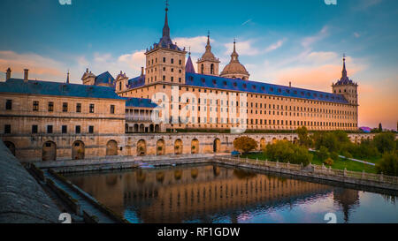 Coucher du soleil derrière les belles El Escorial palace et le monastère du San Lorenzo de El Escorial avec les Frailes Jardin et reflets dans l'étang. Banque D'Images