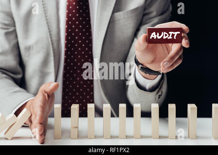 Portrait of businessman holding brique avec 'audit' mot et la prévention de la chute de blocs en bois Banque D'Images