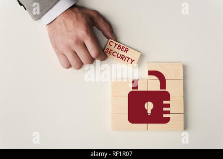 Vue partielle de l'homme tenant brique avec 'Cyber security' sur lettrage blocs en bois avec verrou isolated on white Banque D'Images