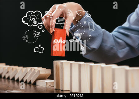 Cropped view of Woman picking bloc rouge avec 'word' capex en bois briques, icônes de premier plan Banque D'Images