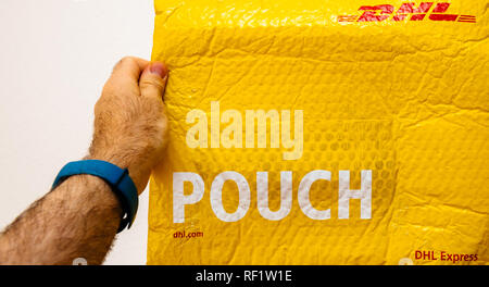 Francfort, Allemagne - MAR 24, 2018 : holding colis DHL Express jaune pouch against white background Banque D'Images