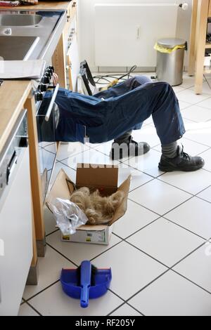 Plombier au travail dans une cuisine, l'installation de drains, les tuyaux de drainage Banque D'Images