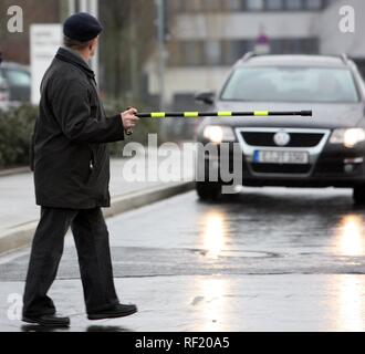 Vieil homme essayant de traverser une rue à l'aide de son bâton de marche de ralentir une voiture venant en sens inverse, Düsseldorf, Rhénanie du Nord-Westphalie Banque D'Images