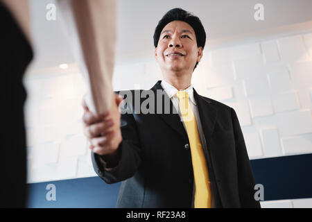Poignée de main entre Happy Asian Manager et Hispanic Businesswoman In Office Banque D'Images