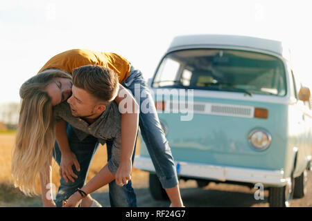 Jeune couple ludique à camper van in rural landscape Banque D'Images