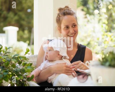 Portrait de Mère détendue avec baby girl on lap sitting on terrace Banque D'Images