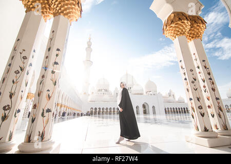 Voyageant par Unated Arabe Unis. Woman in traditional abaya debout dans la Grande Mosquée de Sheikh Zayed, Abu Dhabi célèbre visites. Banque D'Images