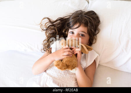 Petite fille au lit avec lapin peluche Banque D'Images