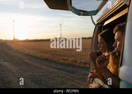 Couple se brosser les dents dans le camping-car en milieu rural au coucher du soleil Banque D'Images