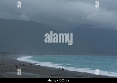 Les gens de la pluie, vent et météo poussiéreux, des eaux bleu azur de la plage de galets, de montagnes centrale sur l'arrière-plan, Chisingtan, Hualien, Taiwan Banque D'Images