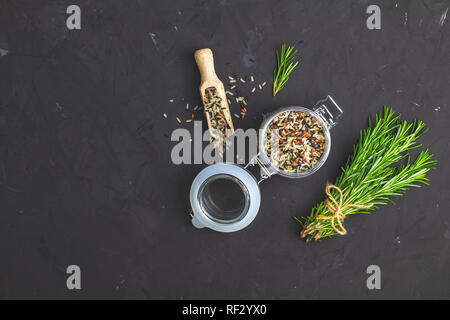 Noir, violet, blanc et le riz (Oryza sativa) mélanger dans un bocal en verre sur Noir pierre béton surface texturée. Vue de dessus avec l'exemplaire de l'espace pour votre t Banque D'Images